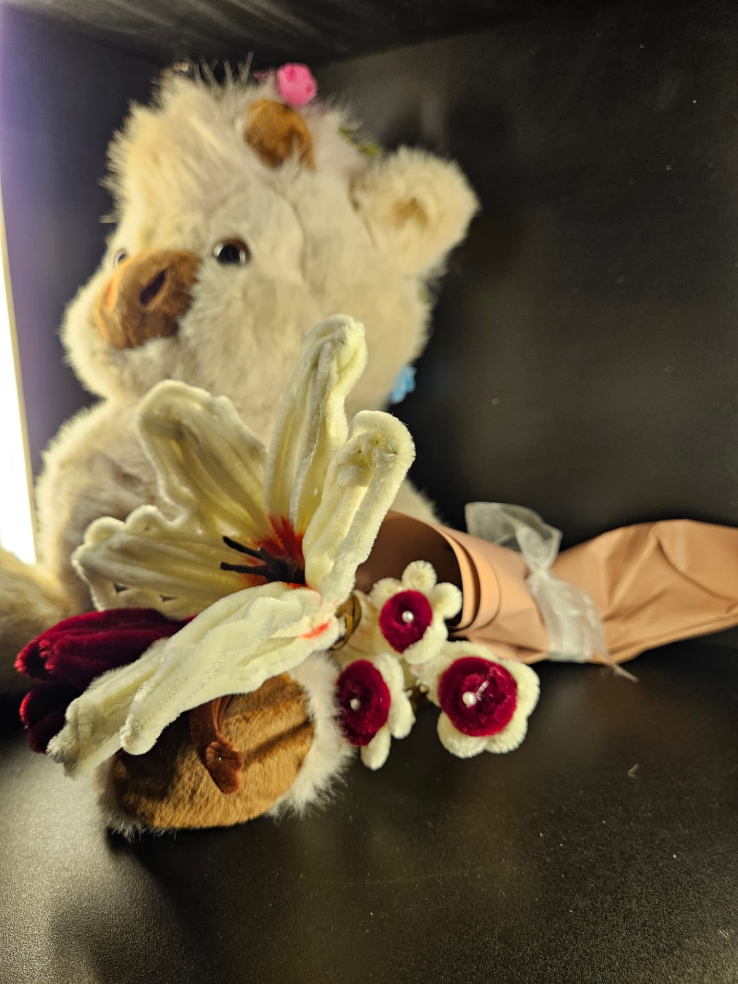 handmade cream and burgundy flowers wrapped in paper beside a teddy bear